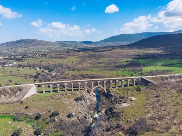 Concrete bridge over mountain river at picturesque green valley