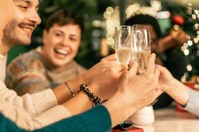 Group of friends making a joyful toast with champagne at a Christmas party.