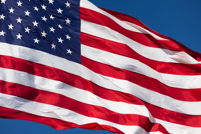 American Flag Waving In Wind Against a Deep Blue Sky.