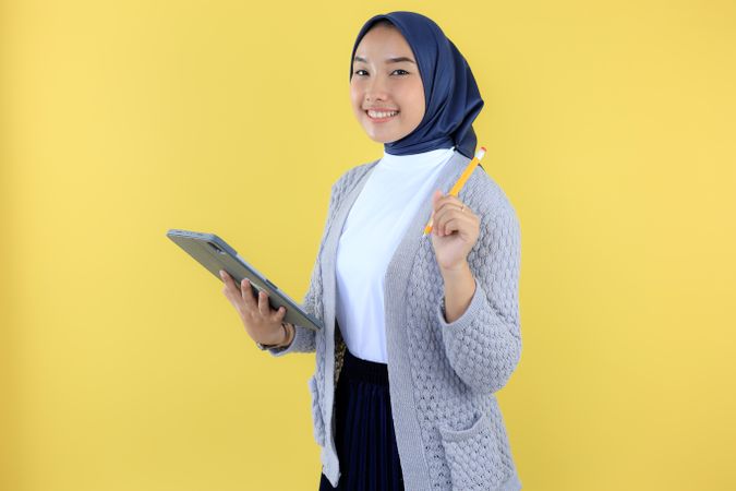 Portrait of Smiling Young Asian Muslim Woman Wearing Hijab Holding Digital Tablet and Magnetic Pen