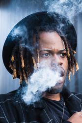 Black man exhaling cloud of smoke on street