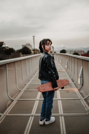 Girl with skateboard on walkway
