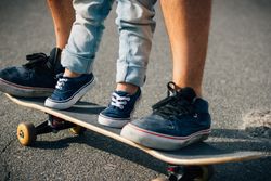 Man with kid training with skateboard on asphalt