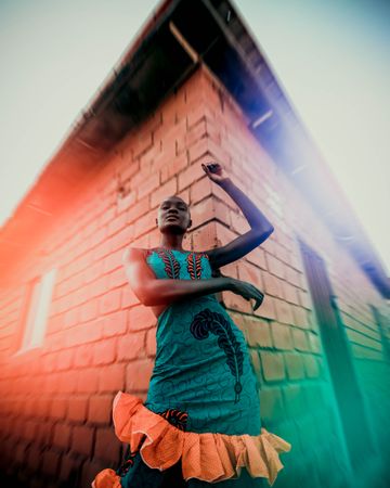 Woman in blue dress standing beside red bricked building