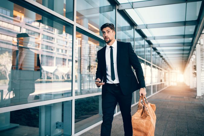 White businessman carrying bag with smart phone at airport