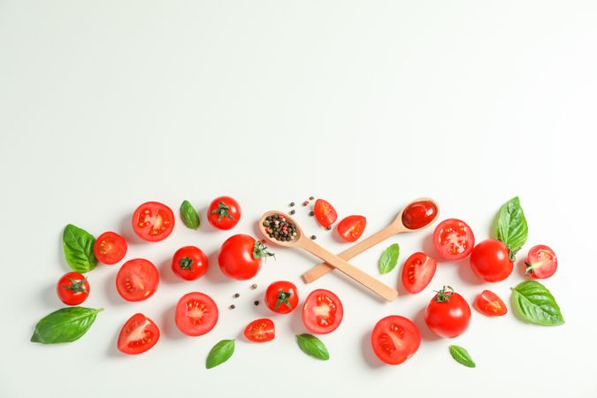Flat lay composition with fresh tomatoes, pepper, basil and wooden spoons on studio background, space for text. Ripe vegetables