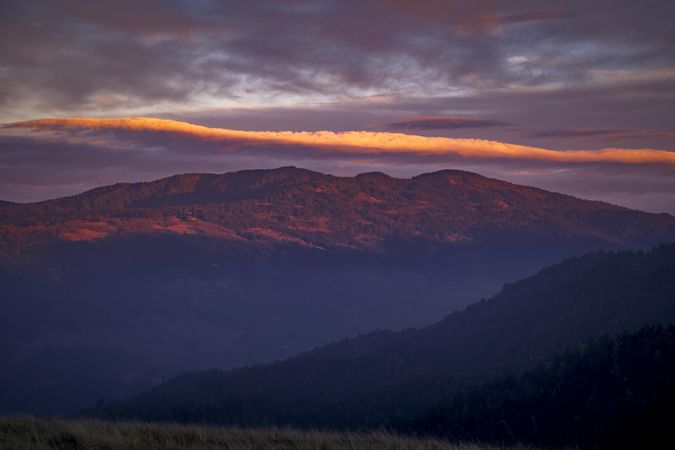 Sunset over a huge mountain on overcast day