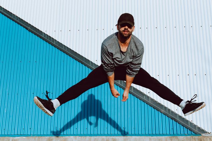 Trendy male flipping and jumping on street