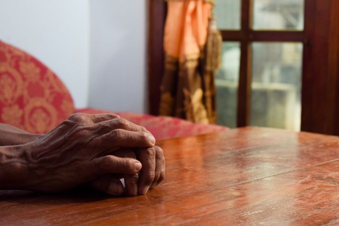 Hands of older person resting on table