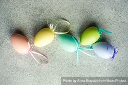 Easter card concept with line of pastel egg ornaments scattered on concrete table 5r9z1d