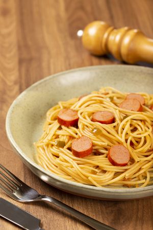 spaghetti pasta with sliced sausages and tomato sauce.