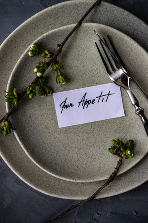Bon appetit note on plate with cherry blossom, vertical composition