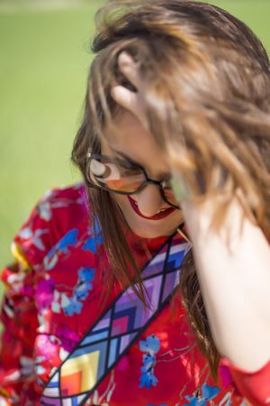 Cheerful woman in sunglasses looking at camera on sunny day