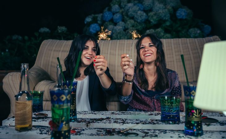Smiling women holding sparklers at a party