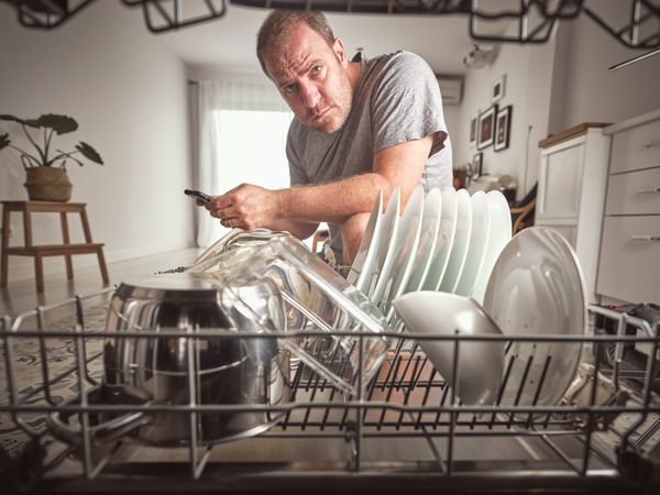Man browsing smartphone near dishwasher