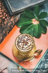 Top view of latte with decorative pattern in chocolate syrup on orange table setting bYvYj0