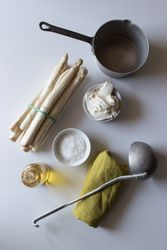 Asparagus and cream amidst kitchenware and condiments
