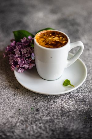 Cup of espresso and lilacs on grey background