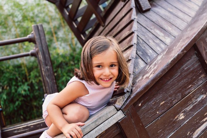 Smiling girl climbing onto wooden playground