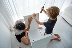 Mother and son assembling wooden furniture in living room