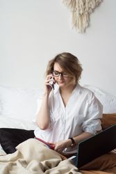 Woman Working From Home In Bed Take Call On Phone