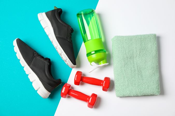 Flat lay composition with towel, dumbbells, fitness bottle and sneakers on color background