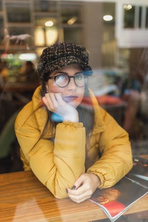 Stylish woman with magazine sitting in cafe