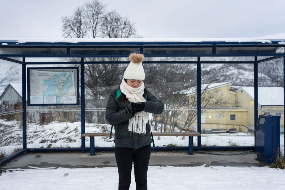 Asian woman waiting for bus in snowy outdoors