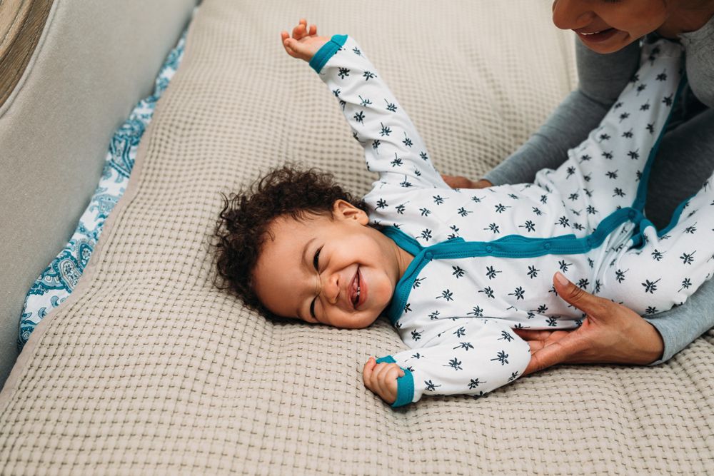 Giggling baby boy lying down with his mother