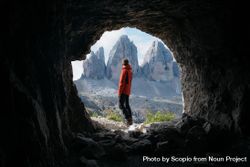 Man in red jacket standing beside cave near mountains 56zad5