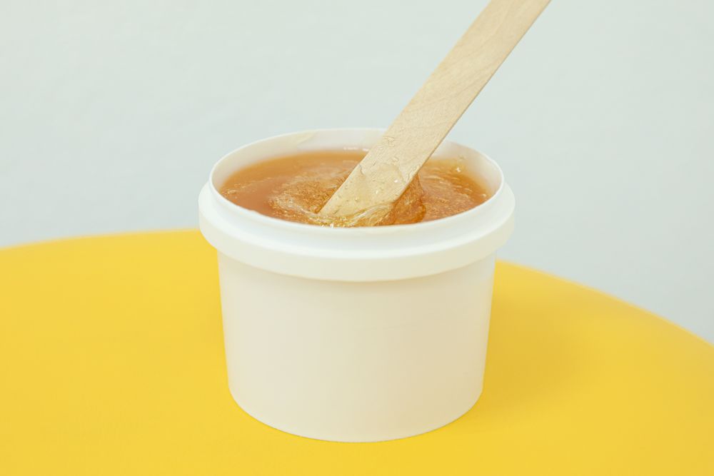Liquid yellow paste for sugaring on yellow background, space for text