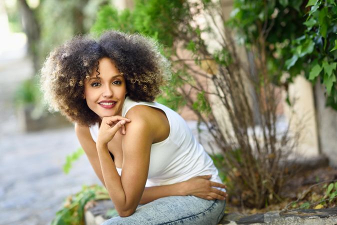 Young Black woman with afro hairstyle smiling while sitting outside