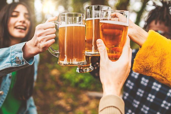 Fun multi-ethnic group of friends gather outside to chat and have a beer together