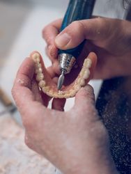 Crop person polishing implants of jaw of denture