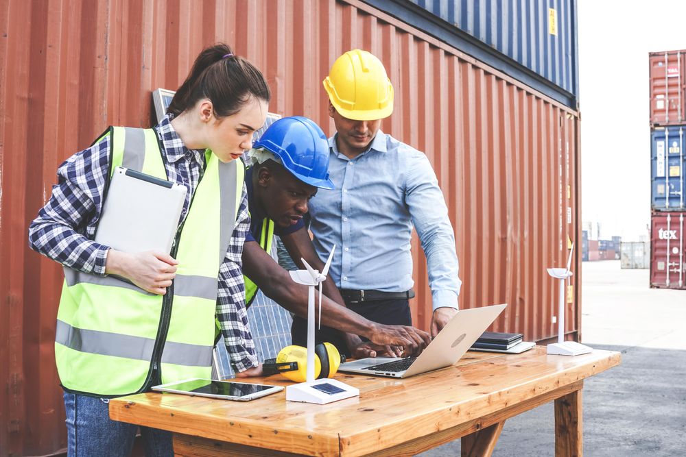 Group of people surrounded by shipping containers discussing solar power