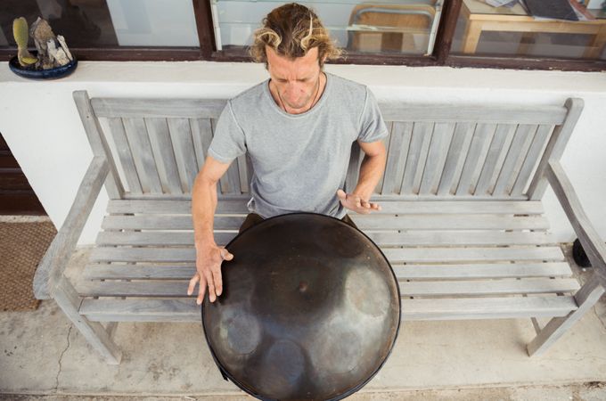 Blond man sitting on bench with big hand drum