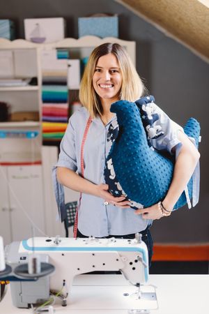 Cheerful seamstress with toy pillow