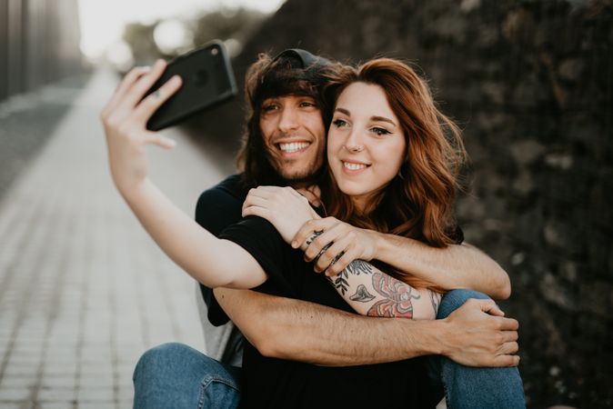 Skaters sitting on road and taking selfie on smartphone