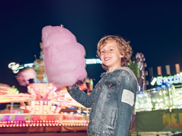 Cheerful boy with cotton candy in amusement park