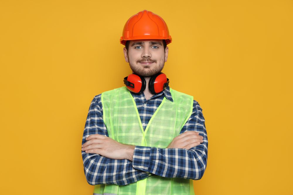 Young man civil engineer on yellow background