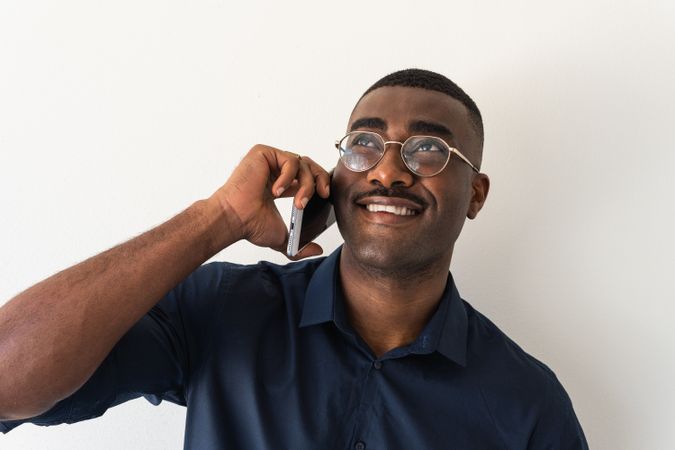 Black man with phone near white wall
