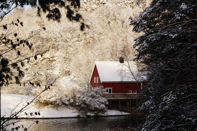 Lonely house in snowy forest on riverside