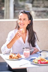 Positive female eating delicious croissant while enjoying breakf