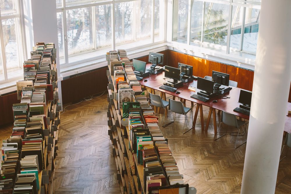 Top view of computer desktops beside bookshelves in school library