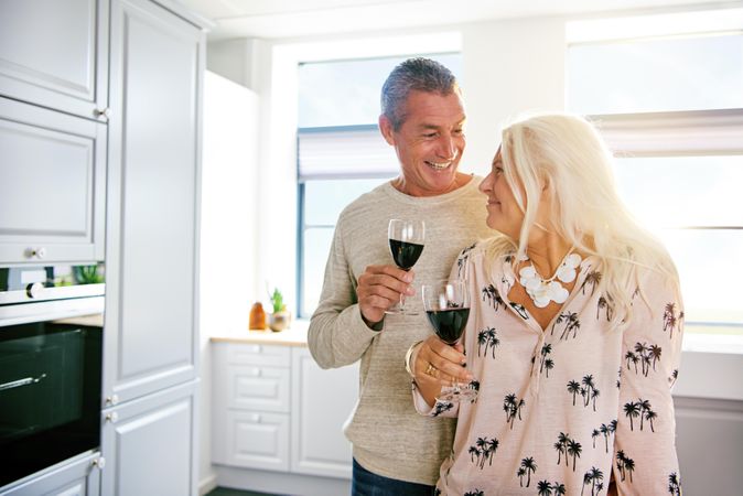 Loving older couple with red wine in a kitchen