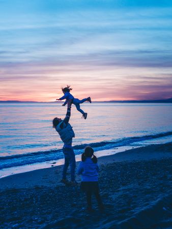 dad rocking kid at the beach