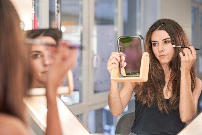 Woman with mirror applying makeup