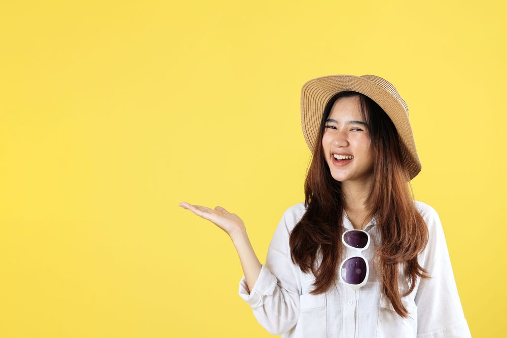 Portrait of Asian Woman Posing using Summer Hat on Yellow Background