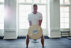 Man lifting heavy weights in bright gym
