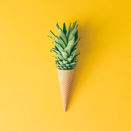 Ice cream cone with pineapple top on yellow background
